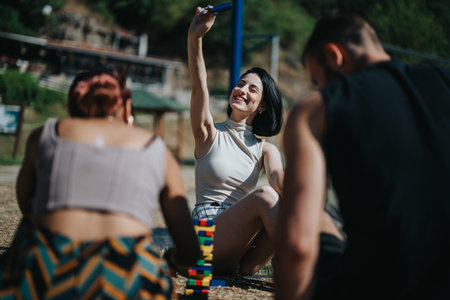 Friends enjoy outdoor summer selfie and building blocks game in the park