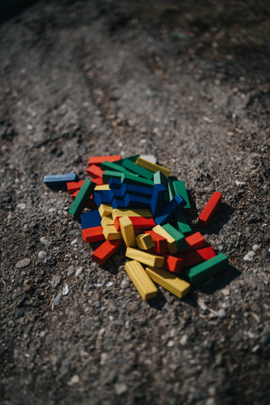 Colorful wooden blocks scattered on gravel in an outdoor play scene for kidsの写真素材