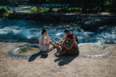 Friends enjoy outdoor riverbank day playing colorful tower blocks by the waterの写真素材