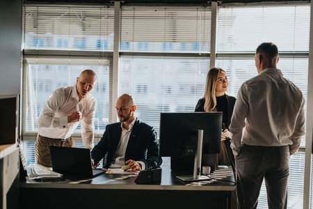 Business colleagues collaborate in a modern office with laptops, monitors, and a discussing...