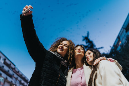 Three friends take a selfie outdoors at dusk, capturing a joyful moment together