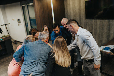 Group of colleagues in a lively office huddle during team building and celebration