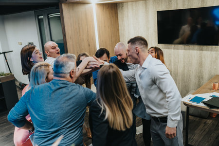 Group of coworkers celebrate together with high-five in a modern office settingの写真素材