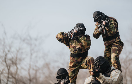 Paintball team in camouflage gear aiming markers during an outdoor match
