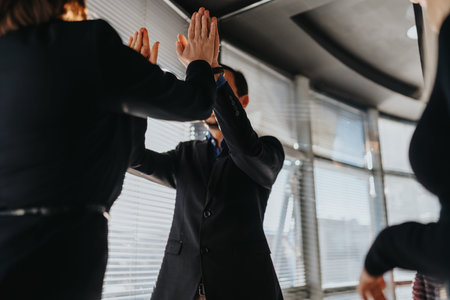Business colleagues give high five in office, celebrating teamwork, success, and positive collaboration.の写真素材