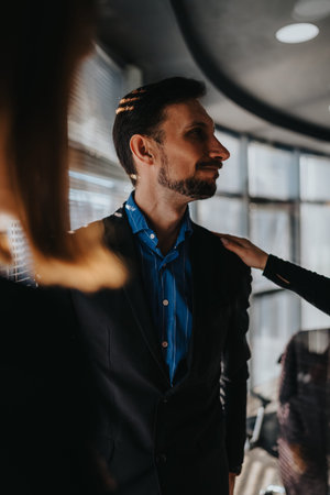 Professional man in blue shirt and suit being touched on shoulder in an office settingの写真素材