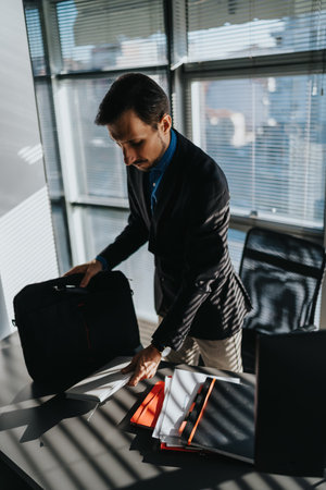 Business professional packing a briefcase in a modern office with documents and laptop on desk