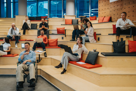 Diverse team in a modern tiered workspace with laptops, cushions, and collaborationの写真素材