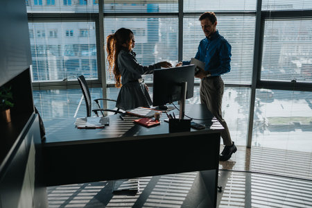 Business professionals shake hands by a desk in a modern office during a collaboration