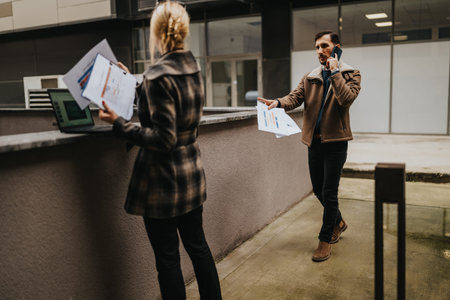 Businesspeople exchange documents outside an office while one speaks on the phone