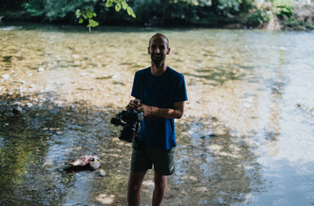 Man with camera by the riverside wearing NASA shirt, outdoor photography session