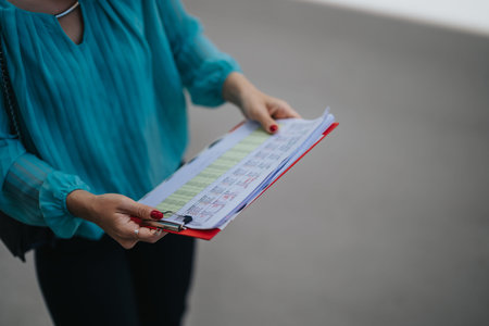 Businesswoman holding clipboard with schedule and documents while checking appointmentsの写真素材