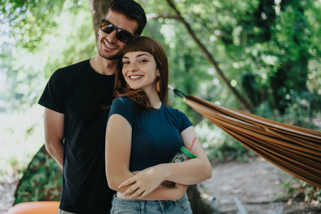 Happy couple outdoors by a hammock enjoying a sunny day together in natureの写真素材