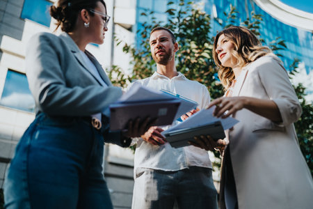 Business team outside a modern office building discussing documents and collaborating on projects