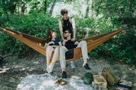 Three friends relax in a hammock during a sunny forest camping trip