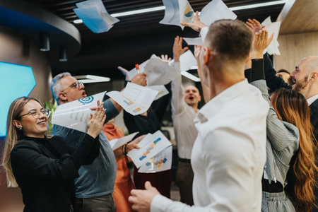 Celebrating a diverse team in the office as papers fly in the air