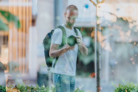 Photographer with backpack taking a photo through glass in an urban city scene