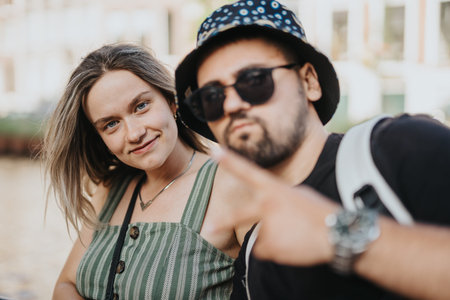 Two friends posing by a canal in Amsterdam during a sunny city outing
