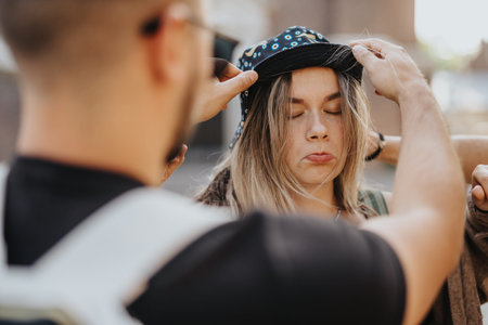 Two friends in Amsterdam adjust a bucket hat during a candid outdoor moment