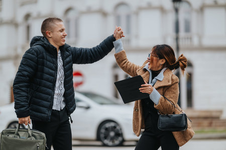 Two friends share a high five on a city street with bags and a clipboard