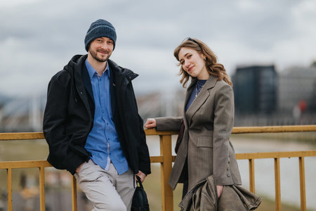 Casual business associates smiling on a city bridge during an overcast day in smart casual attire