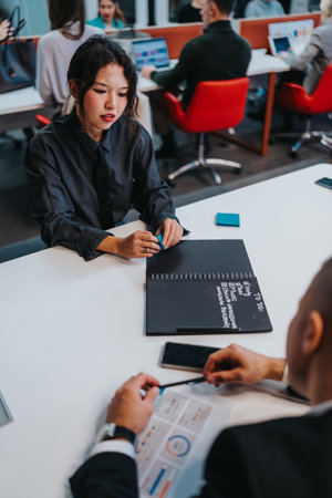 Professional woman concentrates on a notebook during a team meeting at a modern office