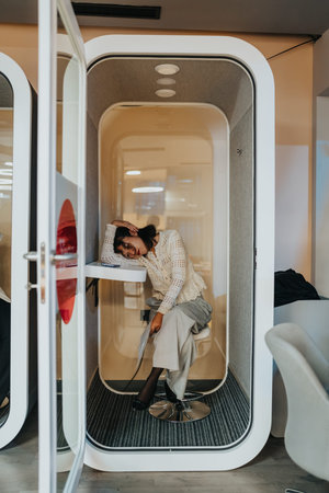 Businesswoman resting in a modern office pod, a private space for focus and calls
