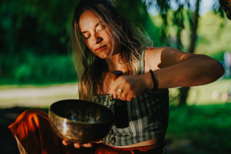 Young woman playing a singing bowl outdoors during a relaxed friends gathering in the Netherlands