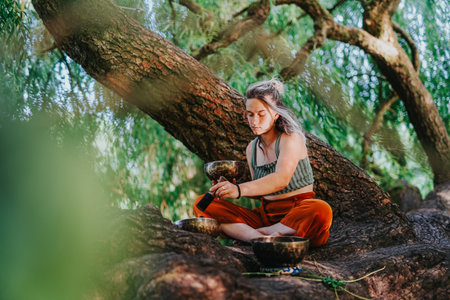 Woman meditating with singing bowls on tree roots in a peaceful outdoor setting in Netherlands