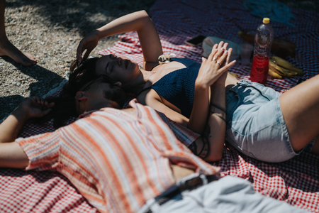 Couple relaxing on a checkered picnic blanket outdoors on a sunny summer day by the river