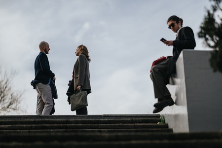 Multicultural business people meeting outdoors on steps while talking and using phone