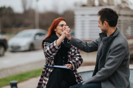 Two colleagues share a high five outdoors, celebrating teamwork and friendly collaboration