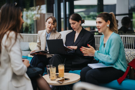 Businesswomen collaborating in an informal meeting with laptop and notes in a lounge