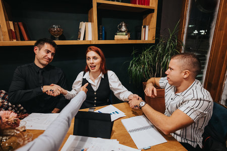 Business colleagues shake hands around a wooden table during a modern office meeting