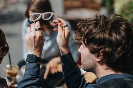 Business coworkers adjusting sunglasses while chatting at an outdoor cafe during a casual meeting