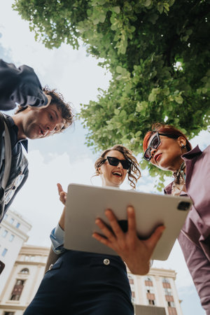 Business coworkers reviewing a tablet together outdoors in a city street during a casual meeting