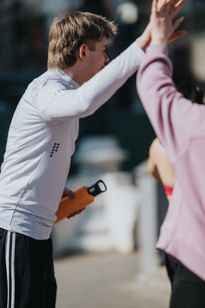 Young man giving a high five to a friend during outdoor fitness training and celebration