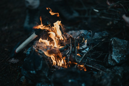 Friends gathered around a campfire on a mountain campsite at dusk warming hands and cooking