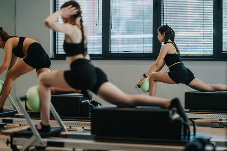 Women doing pilates reformer workout in a modern fitness studio stretching and exercising together