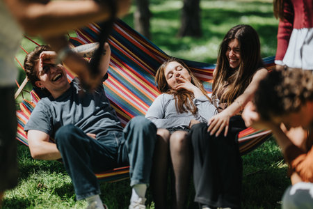 High school students relaxing and laughing together on a colorful hammock in a park