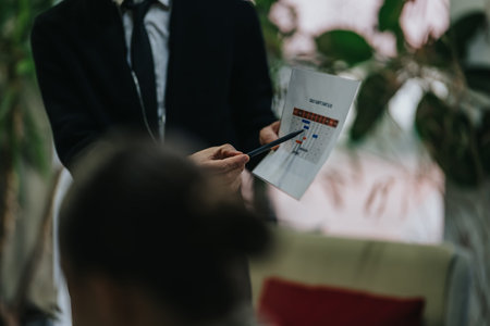 Business person presenting a printed schedule during an office meeting and pointing with a pen