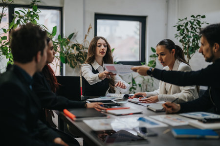 Colleagues in a modern office exchanging documents during a collaborative business meeting around a table