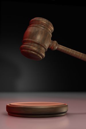 Judge's gavel up illuminated with red light on black backgroundの写真素材