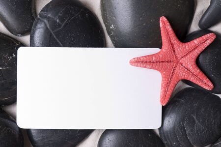 Starfish and white card in black pebblesの写真素材