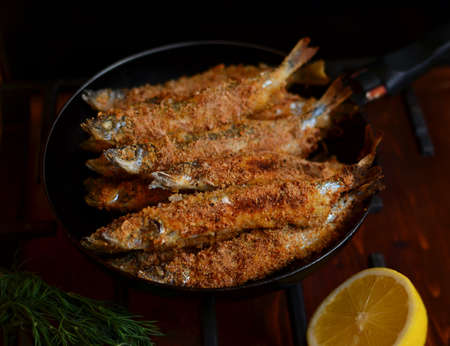 Fried capelin in breading in griddle with lemon and dillの写真素材