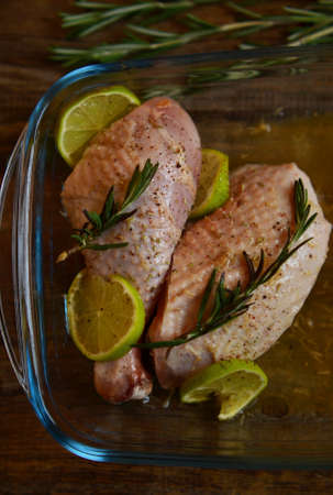 Raw duck legs marinated with rosemary and lime