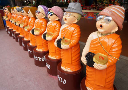 Child monk statue wear an eyeglasses. He's holding alms bowlの写真素材