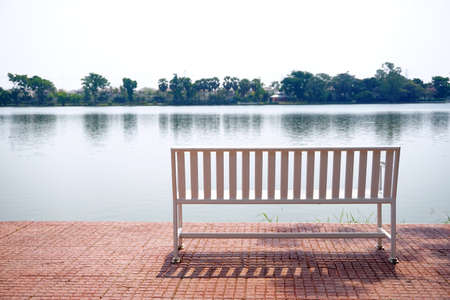 Public resting place with bench. Lake backgroundの写真素材