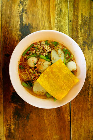 Thai noodle with pork ball in bowl on wooden table.の写真素材