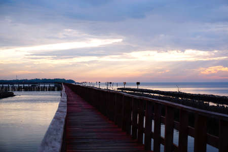 Long simple wooden jetty leading into blue ocean in the gulf of Thailand with sunsetの写真素材